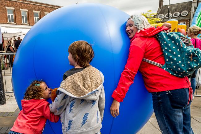 Image of Children and adult lean on large inflatable ball - SHIFT 
