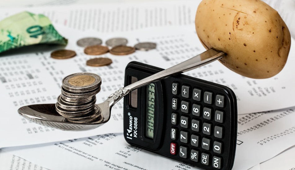 Image showing balancing potato and money on a calculator, illustrating cost of living crisis