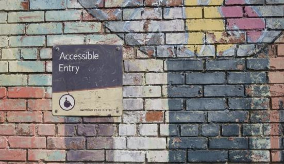 Image of a wall with a sign "Accessible Entry"