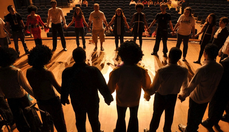 Image of people standing on a stage, holding hands. 