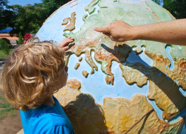 Image of a child next to a large globe outside