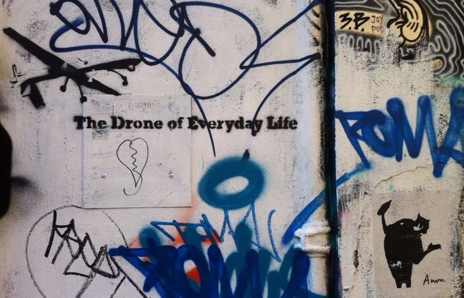 Graffiti on a wall saying "The Drone of Everyday Life" 