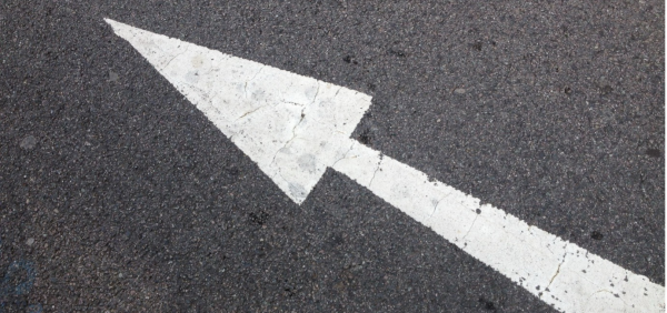 A white arrow on a grey road surface