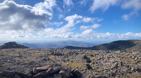 The peak of Scaffell Pike, a rocky landscape with blue skies and white clouds