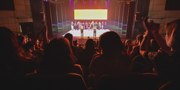A photograph of an audience looking at a stage from height