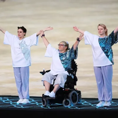 Dancers on a stage, including one wheelchair user and some with ear-protection