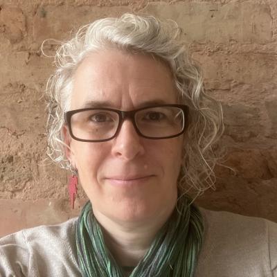 A white woman wearing glasses and a green scarf