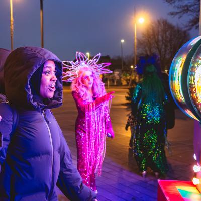 A group of people, including some in fancy dress, look at an illuminated display