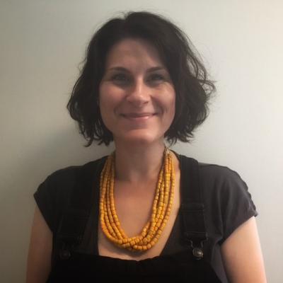 A photo of a white woman with short brown hair wearing a yellow necklace