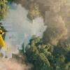 A birds eye view of a small yellow plane flying over a river or a lake broken up with some digital elements