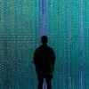 silhouette of a person in front of a wall of blue and green lights